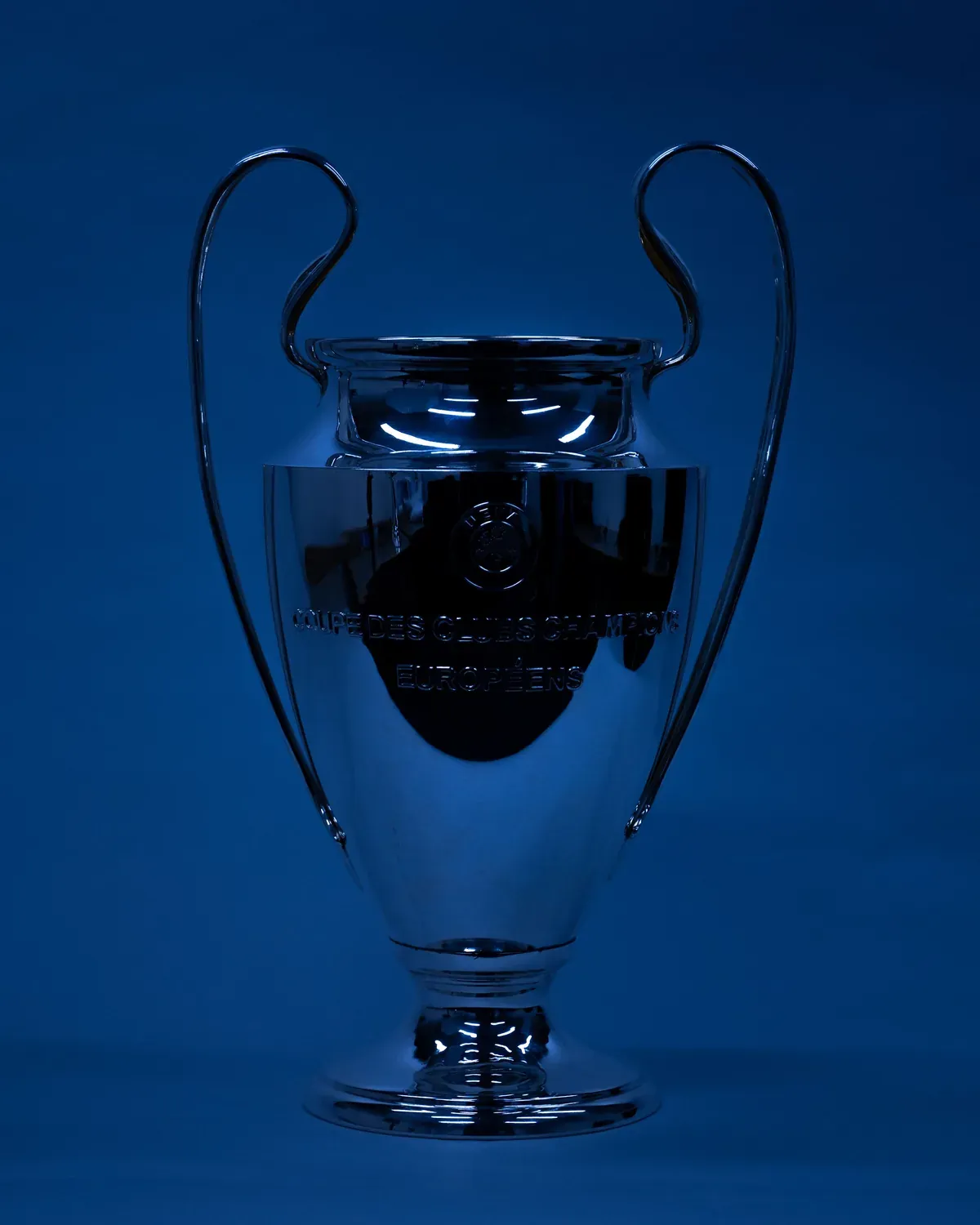 a shiny glass trophy cup on a blue background with the reflection of it's handle